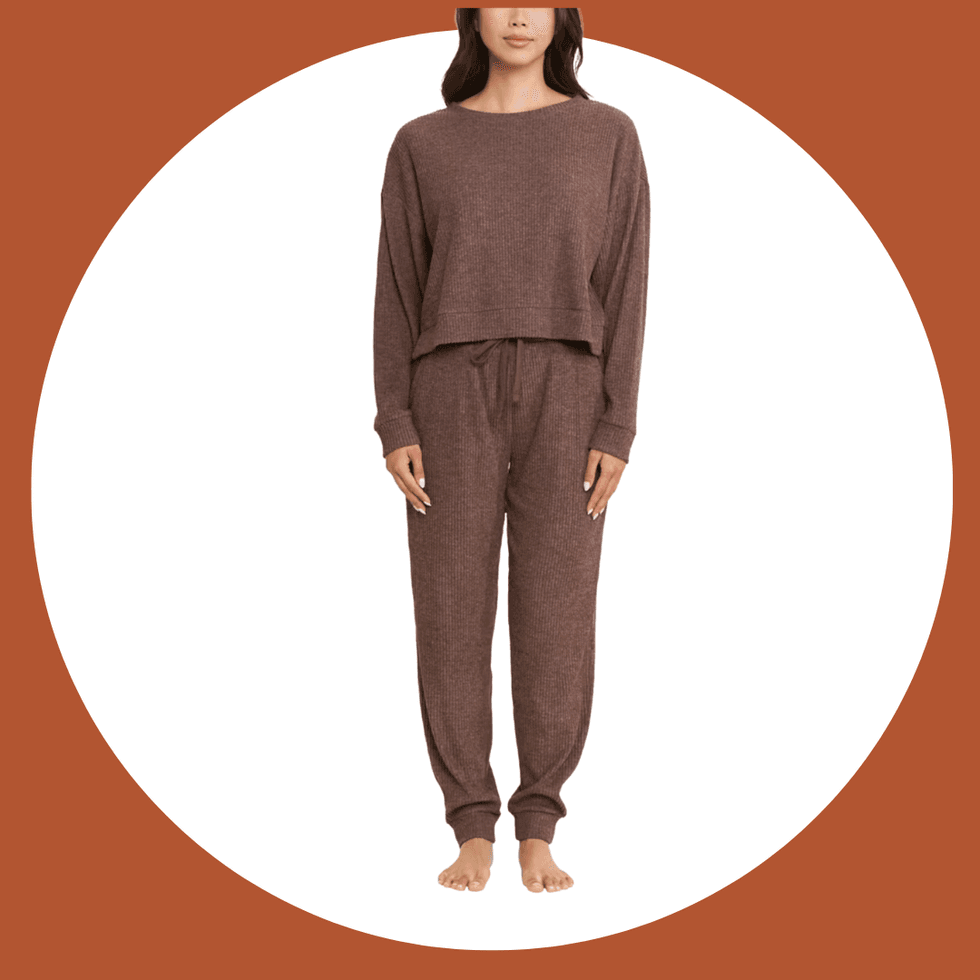 Person in brown loungewear set, barefoot on a white and brown background.