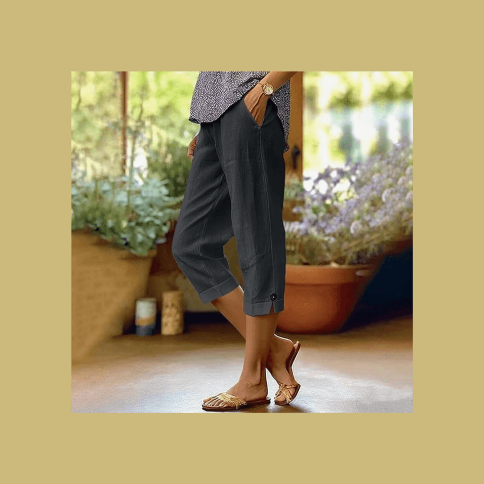 Person in dark capri pants and sandals, standing in a garden setting.