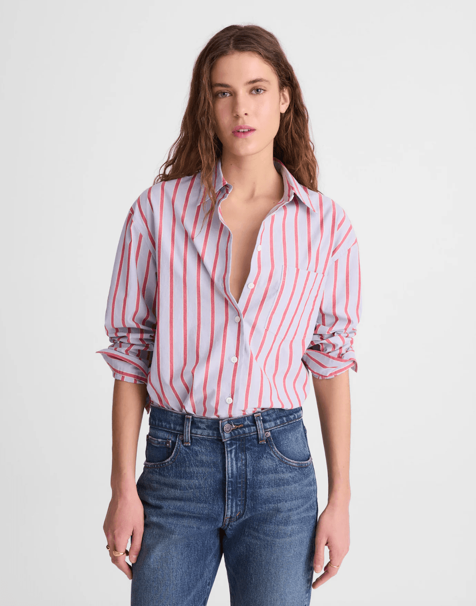 Person in red-striped shirt and jeans standing against a plain background.