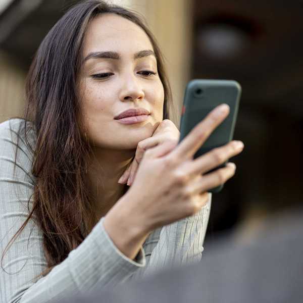 Person looking at a smartphone, with a thoughtful expression.