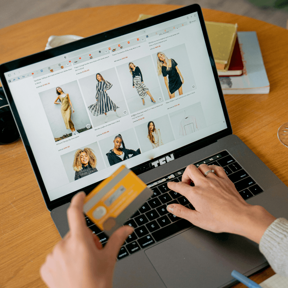 Person online shopping for clothes at a laptop using a credit card