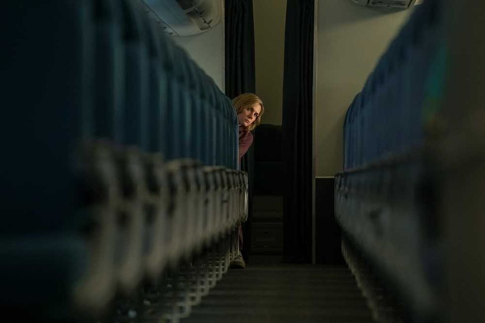 Person peeking into an empty plane cabin, viewed between rows of seats.