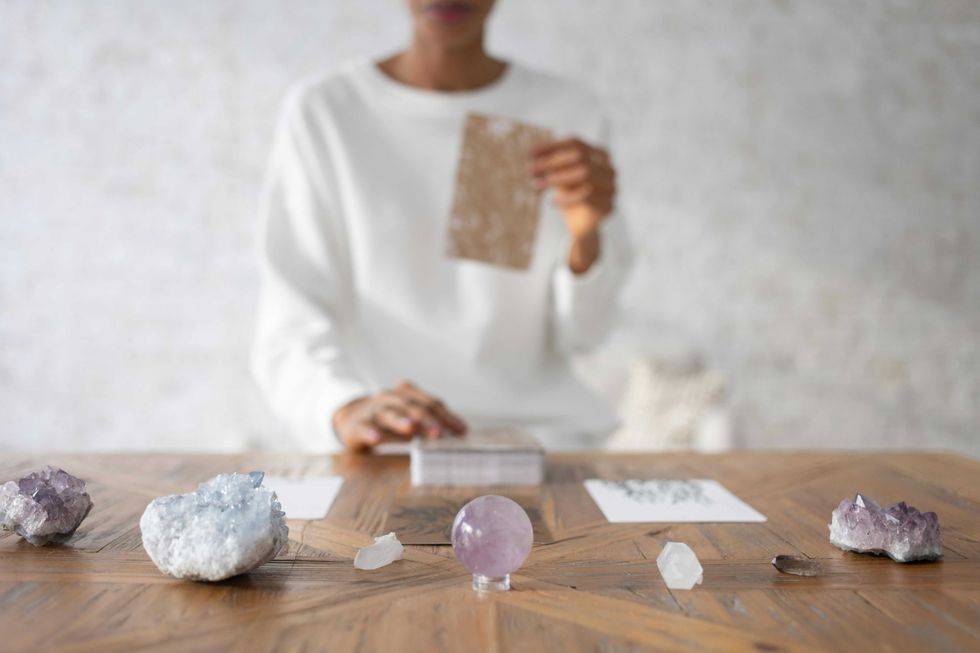 Person reading card with crystals on a wooden table.