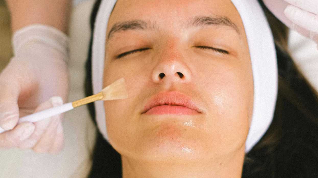 Person receiving a facial treatment with serum and brush applied on forehead.