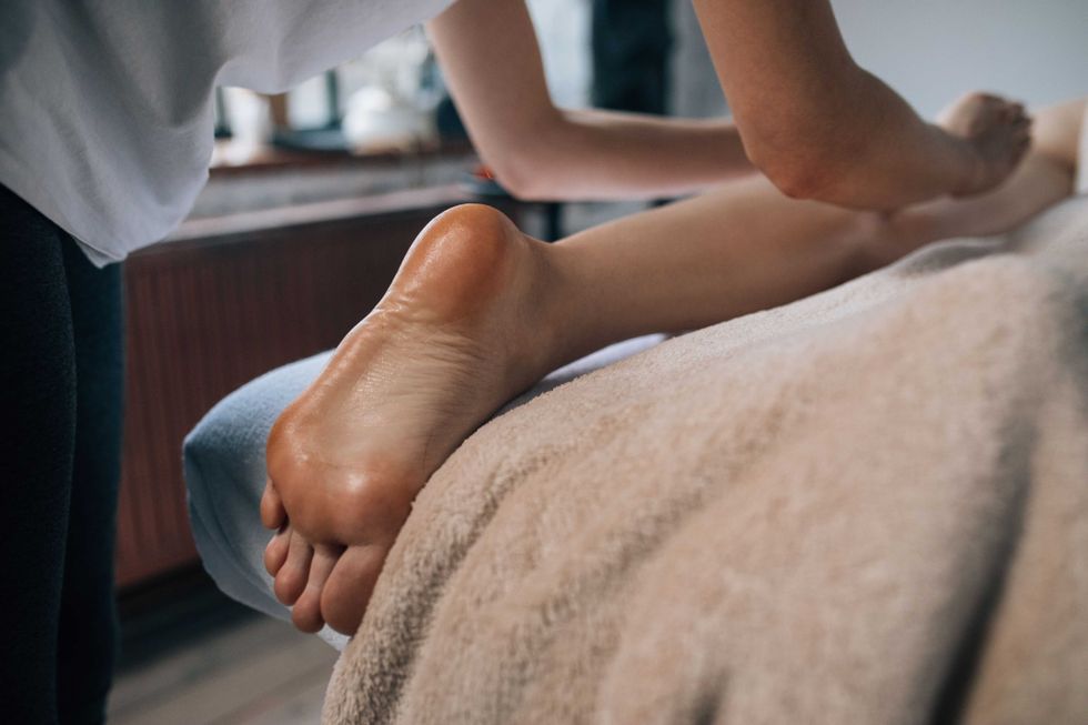 Person receiving a leg massage while lying on a towel-covered table.