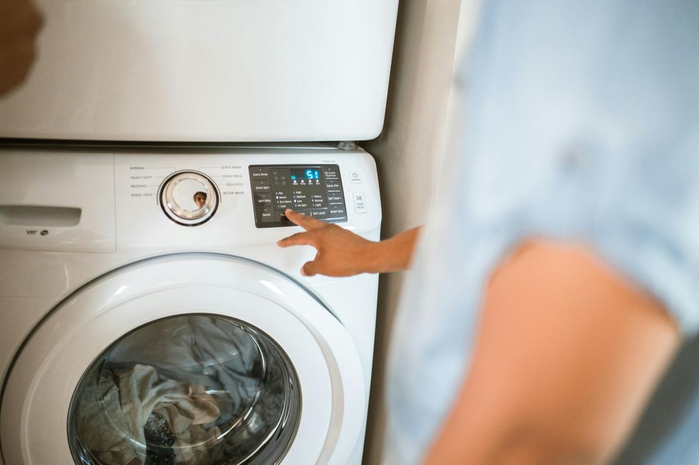 Person selecting settings on a modern front-loading washing machine.