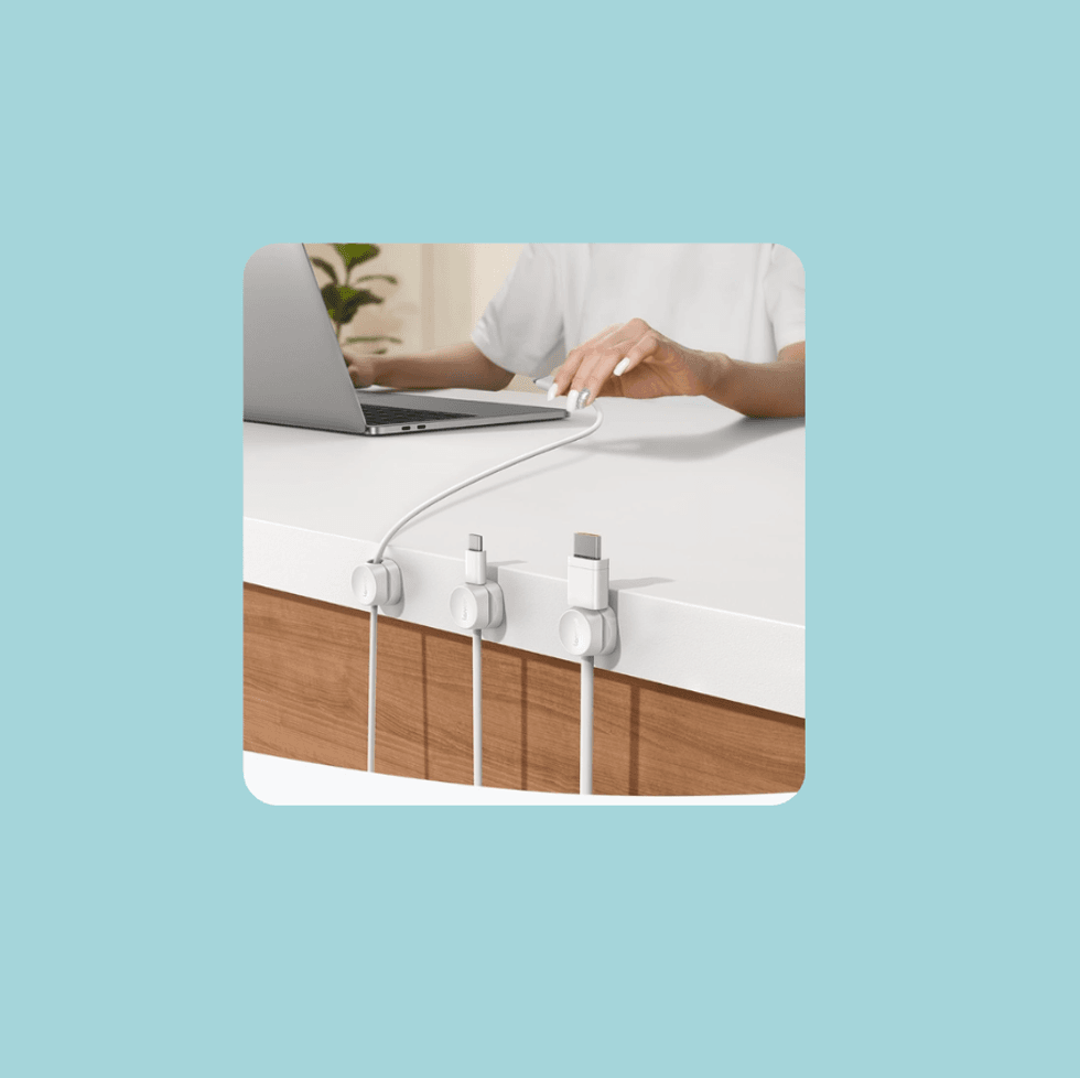 Person using laptop with organized charging cables on desk.