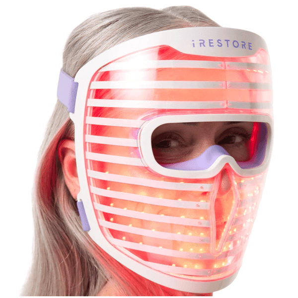 Person wearing a glowing LED light therapy mask.