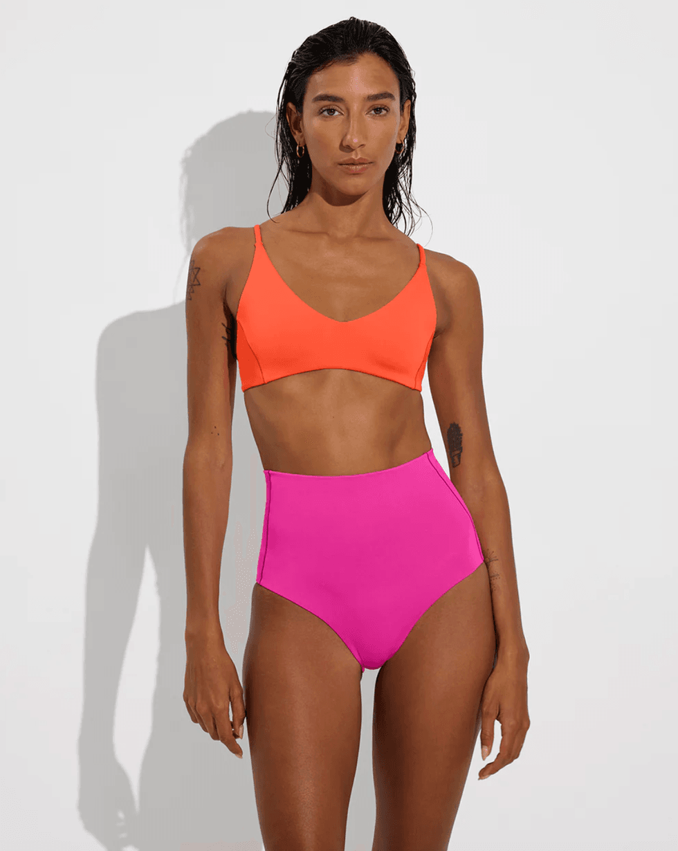 Person wearing a vibrant orange bralette and pink high-waisted bikini bottom.