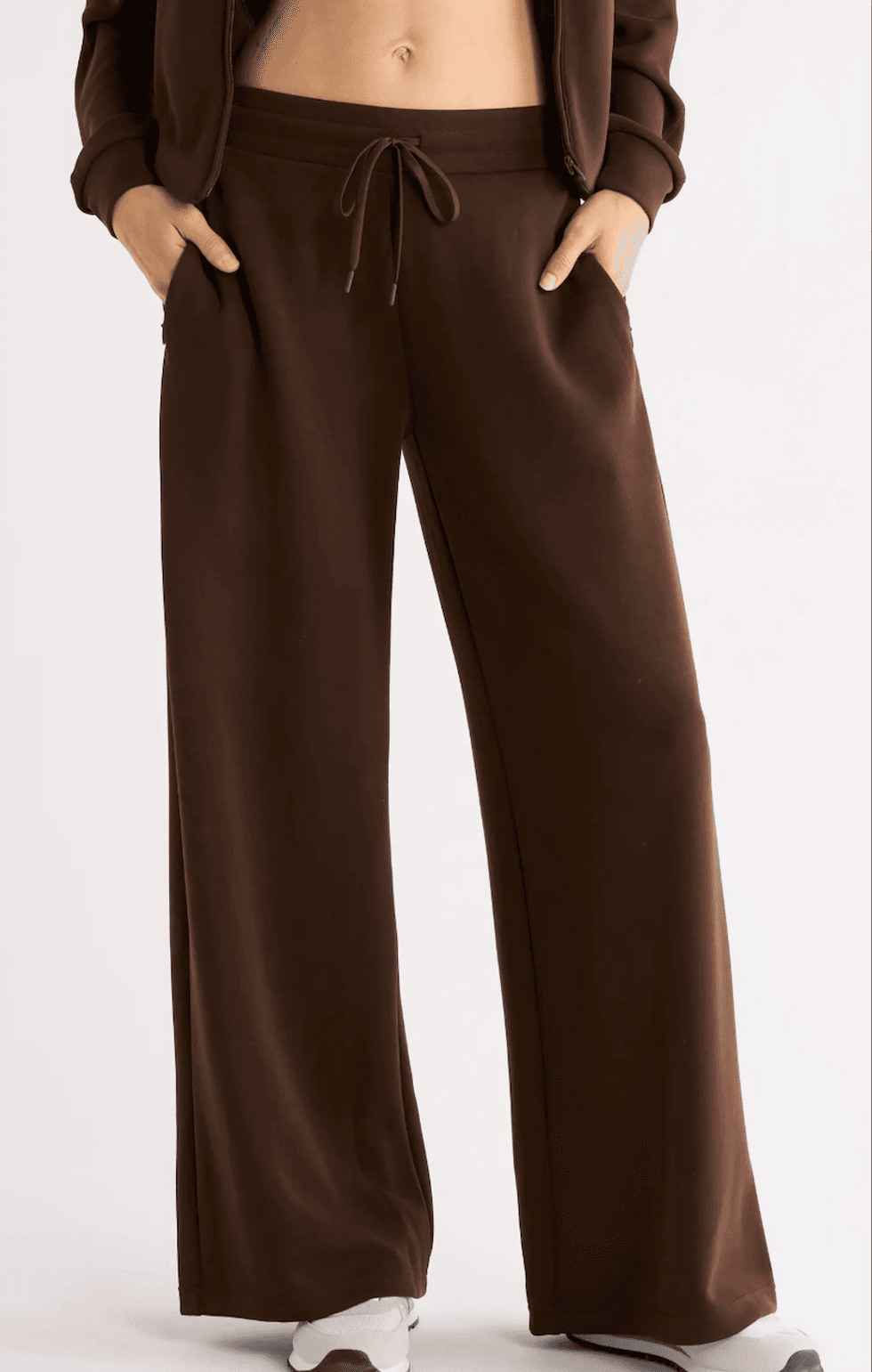 Person wearing brown wide-leg sweatpants, hands in pockets.