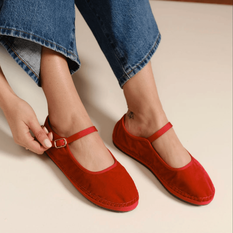 Person wearing red Mary Jane shoes and blue jeans.