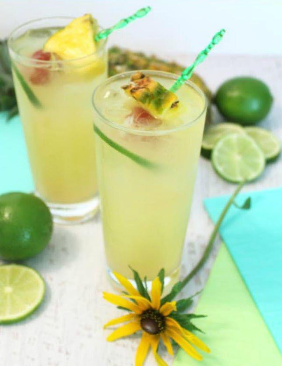 Pineapple Coconut Mojito with flowers, limes, and green and blue napkins