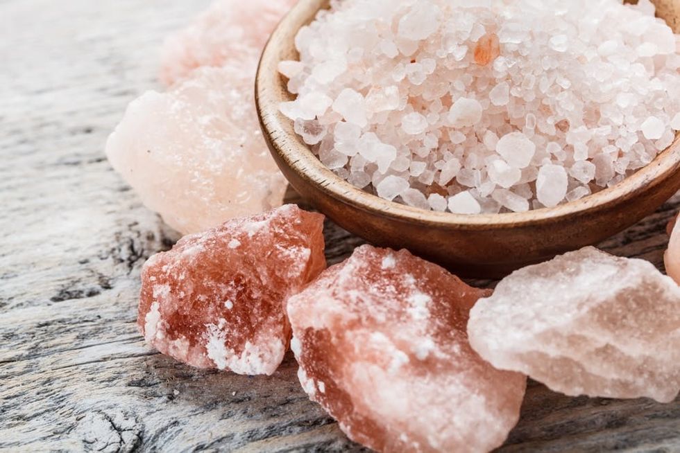 Pink crystals of Himalayan salt rest on a wood table