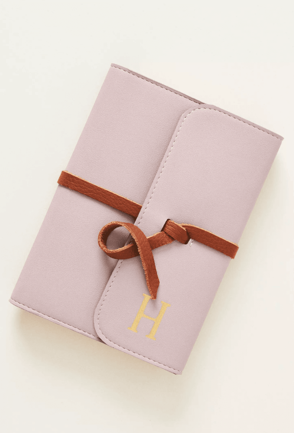 Pink notebook with "H" initial and brown wraparound tie.