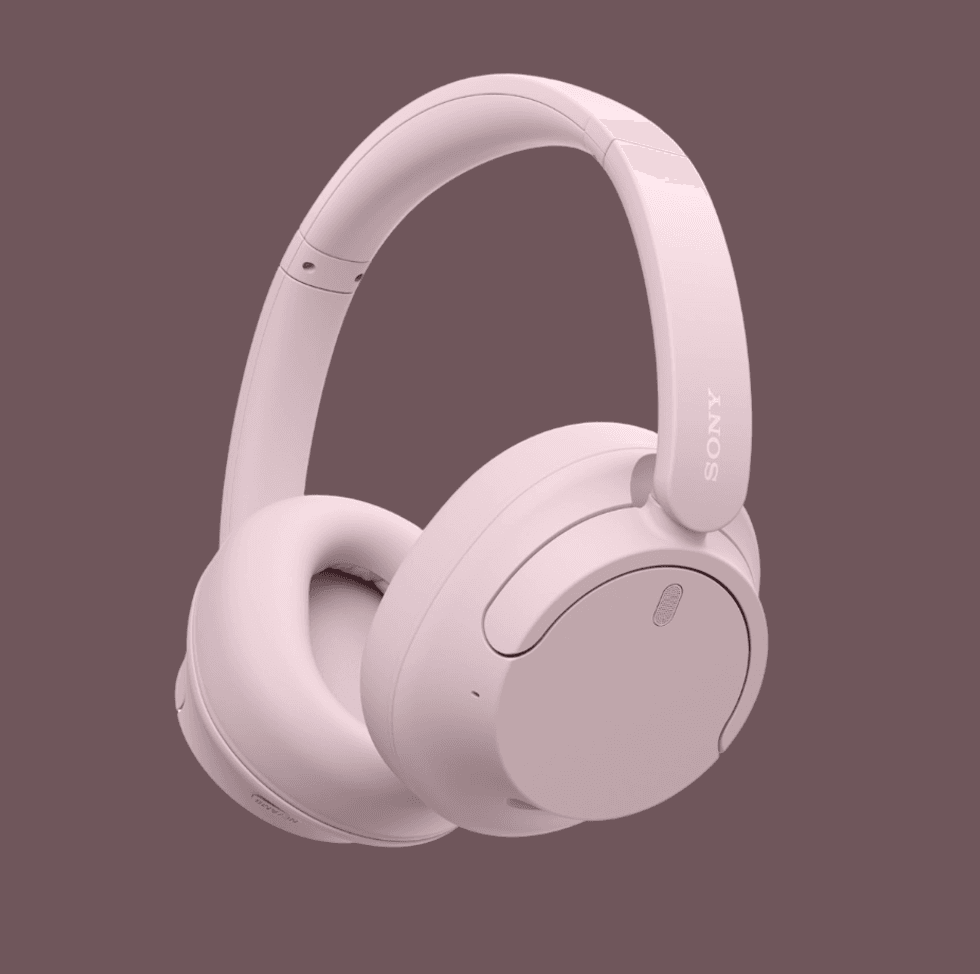 Pink Sony over-ear wireless headphones on a mauve background.
