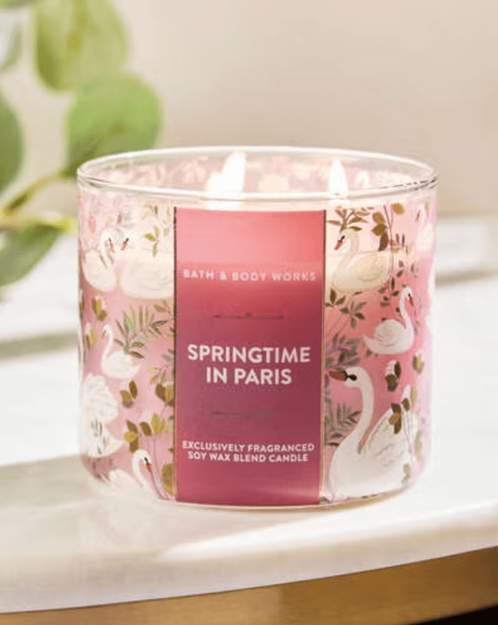 Pink soy wax candle labeled "Springtime in Paris" with swan pattern.