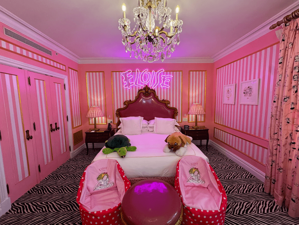 Pink themed bedroom with zebra rug and "Eloise" neon sign.