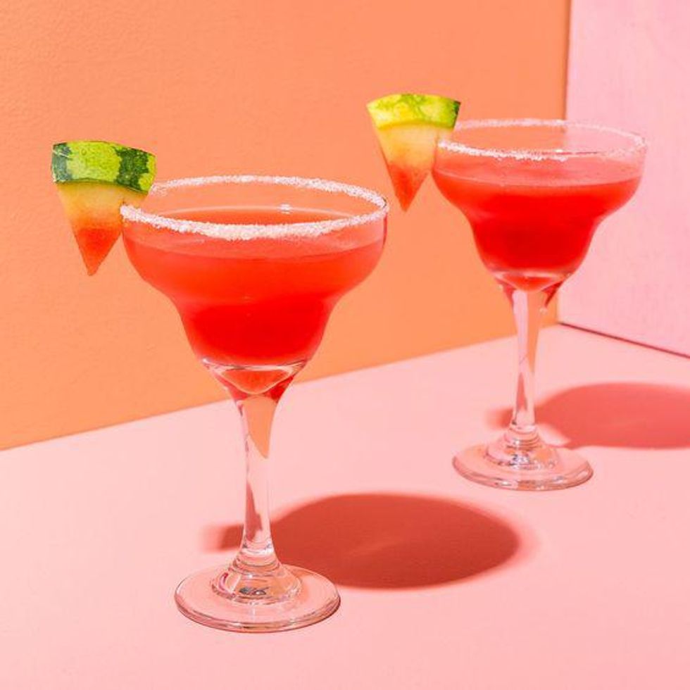 Pink watermelon margaritas in a martini glass on a pink table