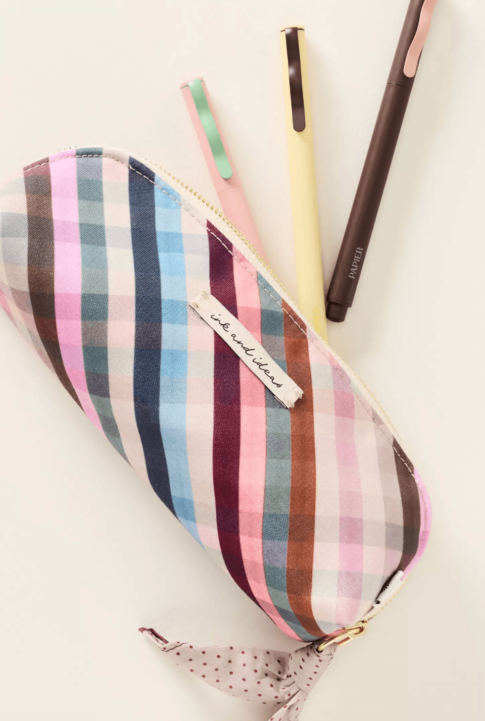 Plaid pencil case with three pens, labeled "ink and ideas," and polka dot ribbon.