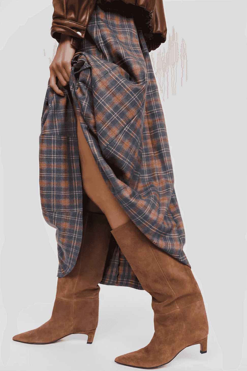 Plaid skirt held up to reveal brown knee-high boots.