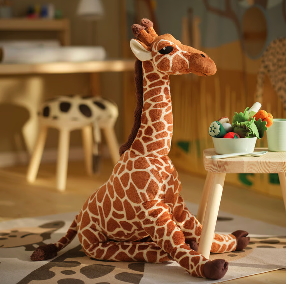 Plush giraffe toy beside a table with toy vegetables in a cozy playroom.