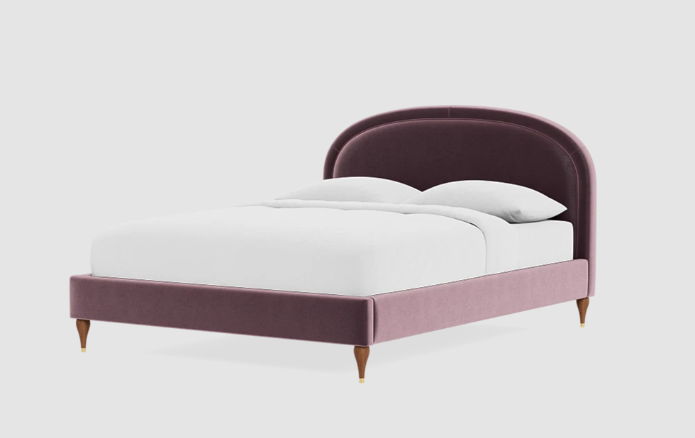 Plush velvet bed with arched headboard, white bedding, and wooden legs.