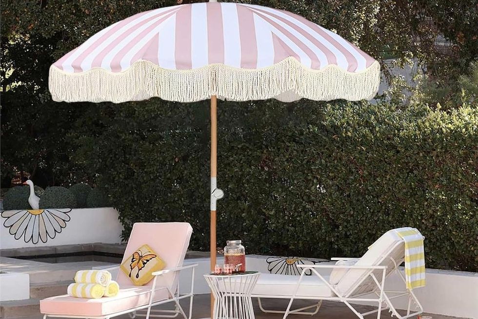 Poolside with loungers, a pink striped umbrella, and floating yellow flowers in the water