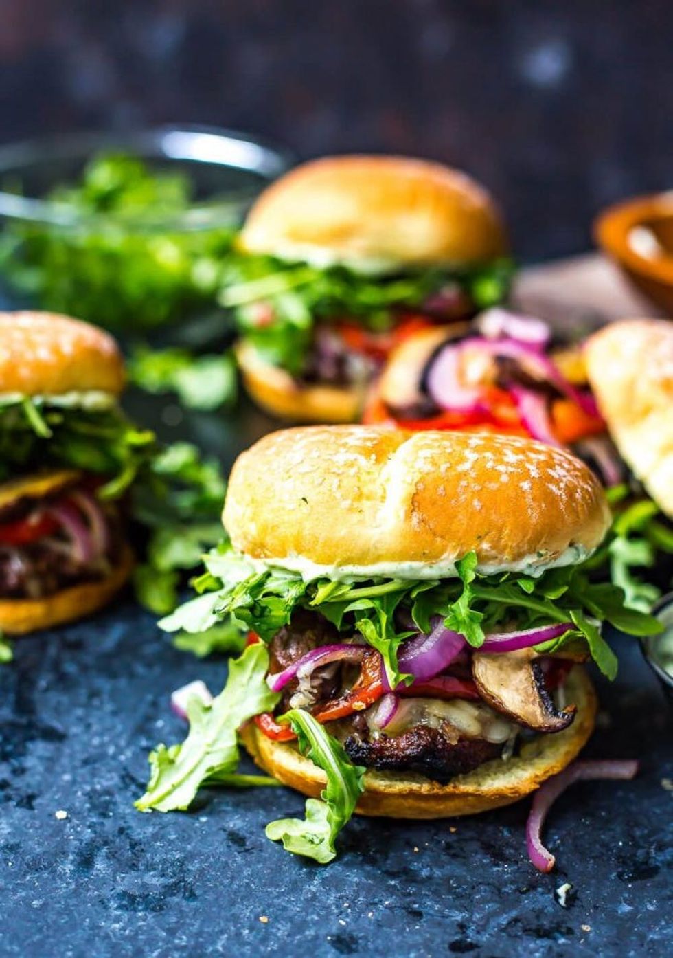 portobello mushroom beef burger recipe loaded with veggies on a blue table
