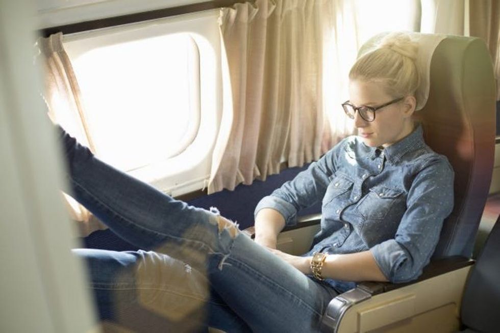 Portrait of young woman sitting on train with feet up