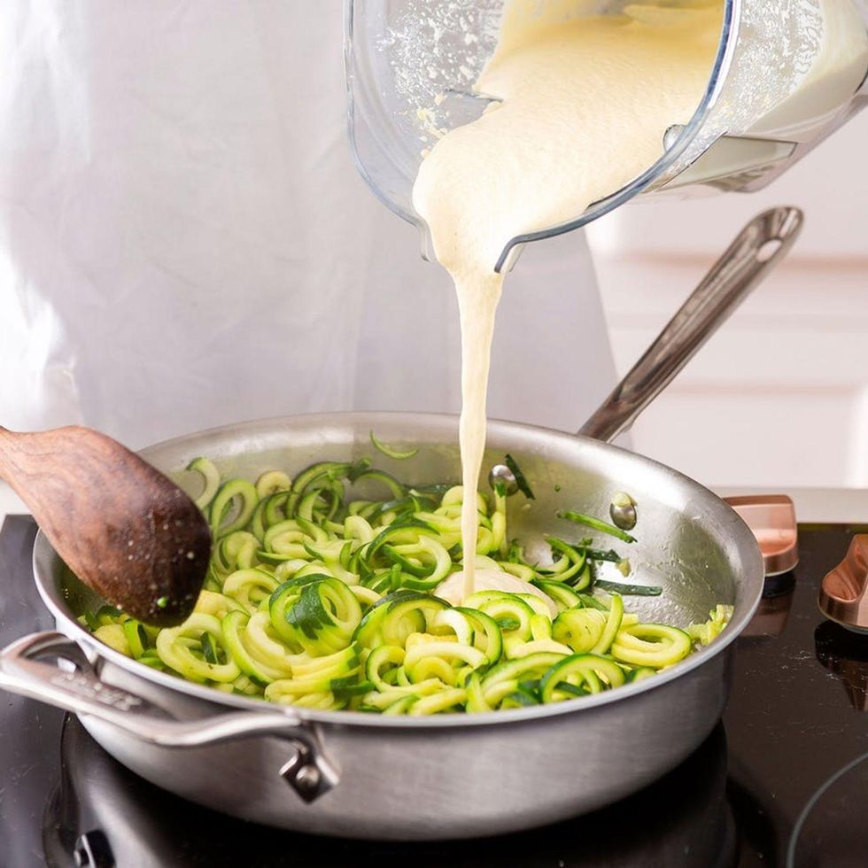 pouring the cheese sauce over the zucchini