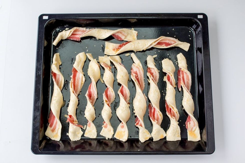 prepping the bacon pastry twists with egg wash and sesame seeds