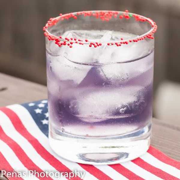 purple cocktail on an american flag napkin with a red rim