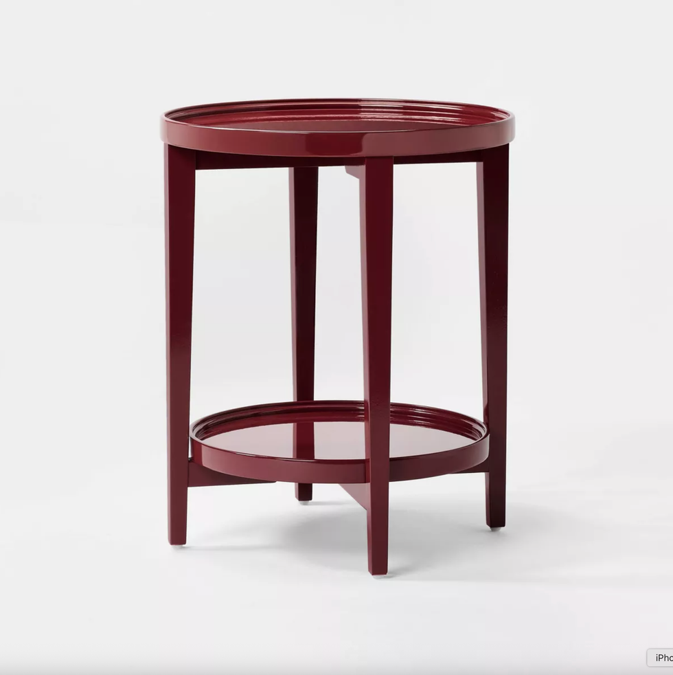 Red round side table with a lower shelf, set against a plain white background.