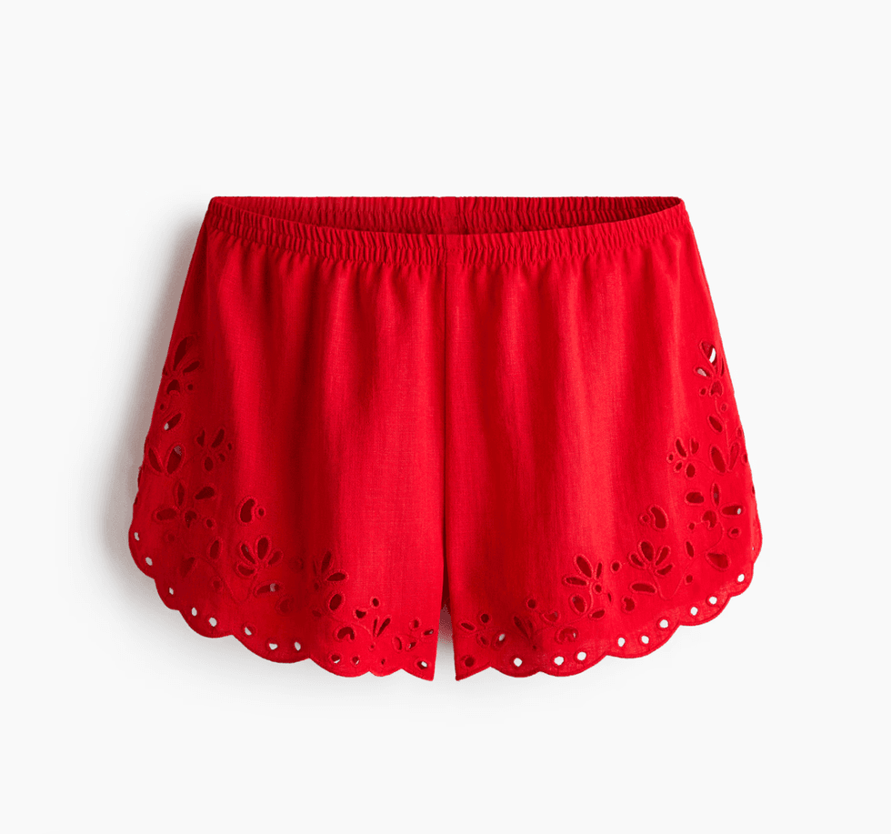 Red shorts with elastic waist and floral embroidery on scalloped hem.
