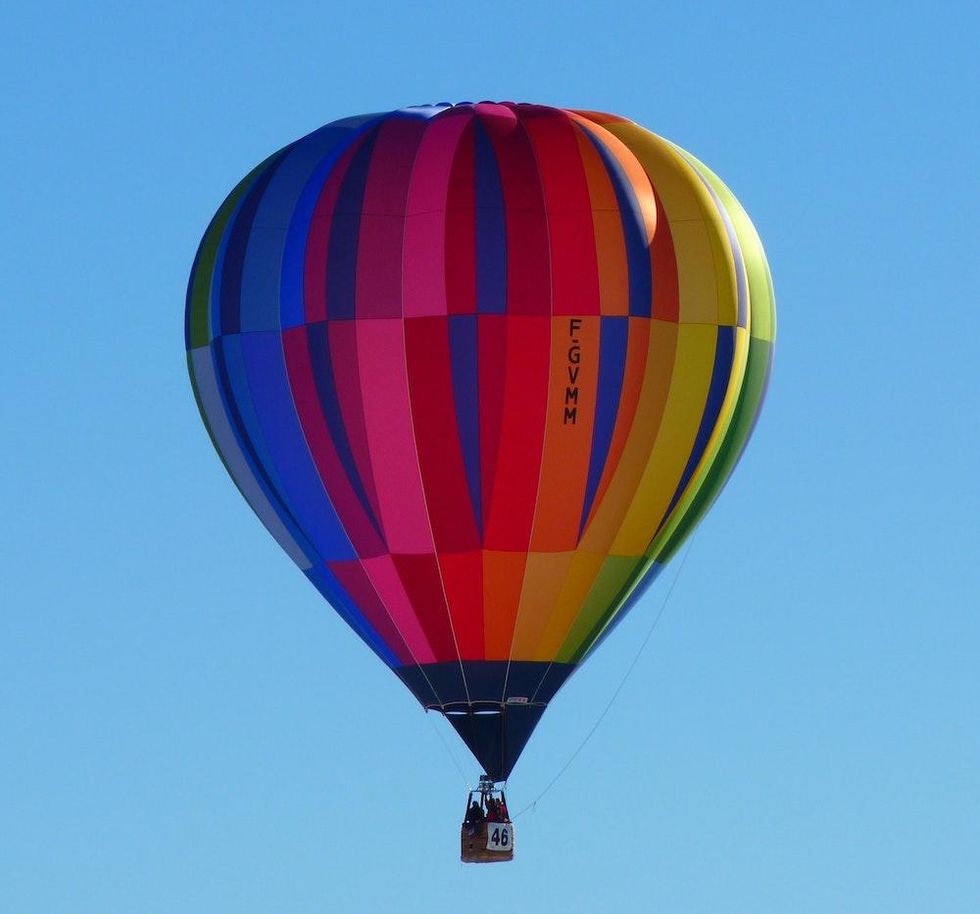 riding in a rainbow hot air balloon against a blue sky
