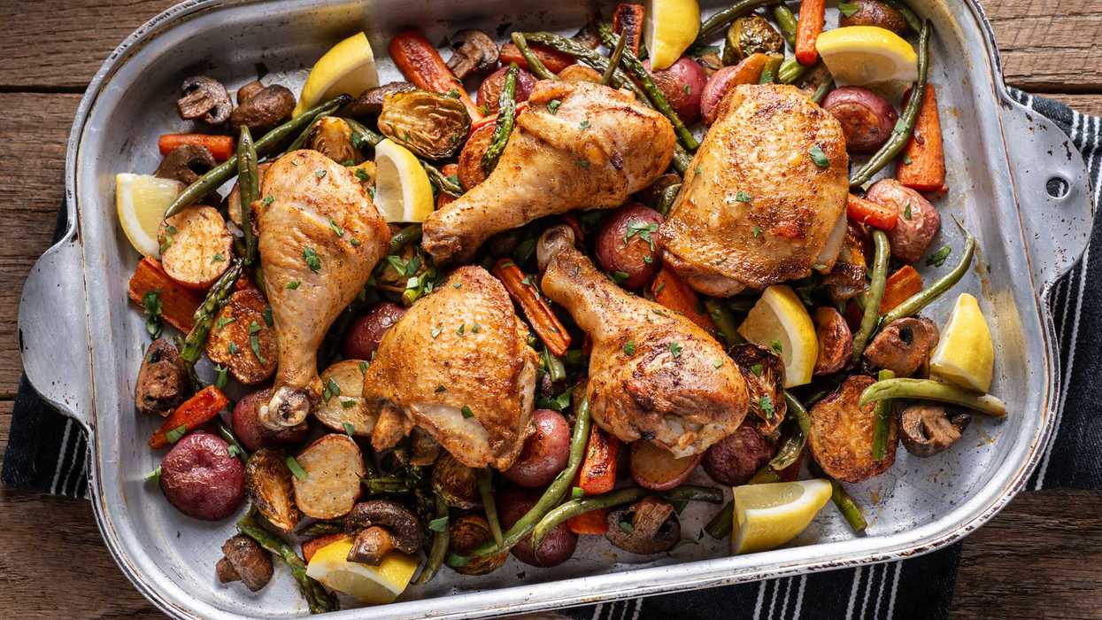 Roasted chicken with vegetables and lemon wedges in a large baking dish.