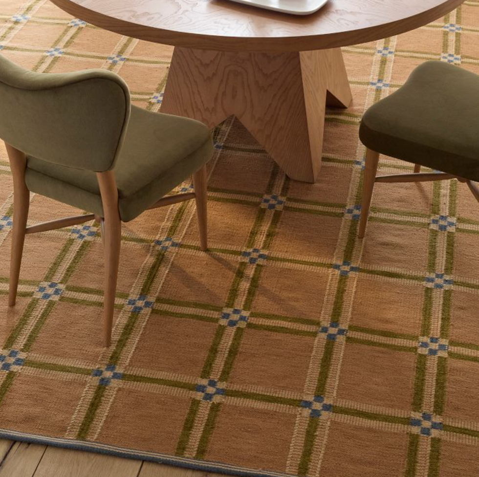 Round wood table, green chairs on plaid carpet with blue accents.