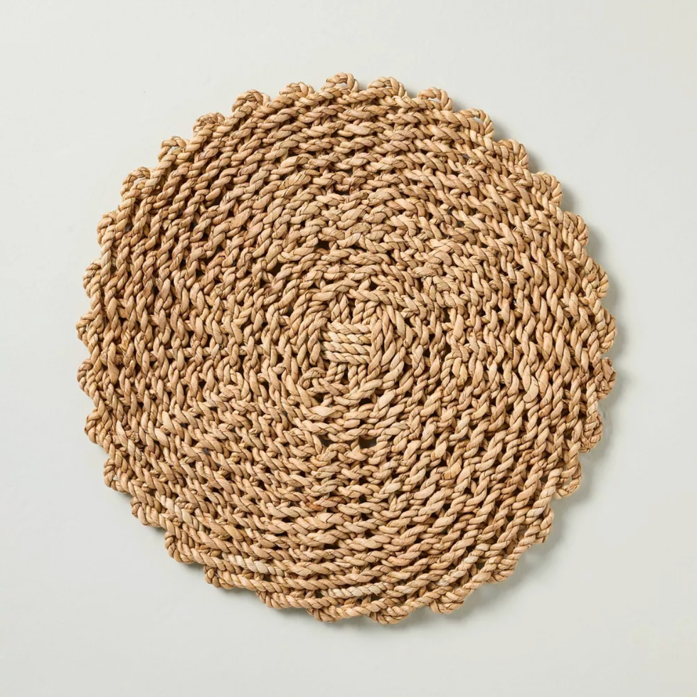 Round woven natural fiber placemat on a light background.