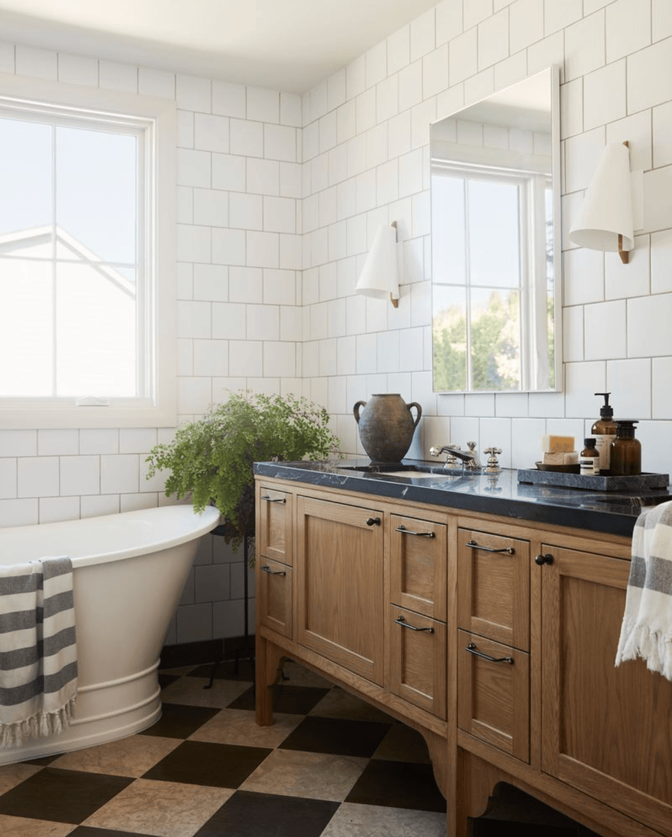Rustic bathroom with a freestanding tub, wood vanity, and checkered floor tiles.