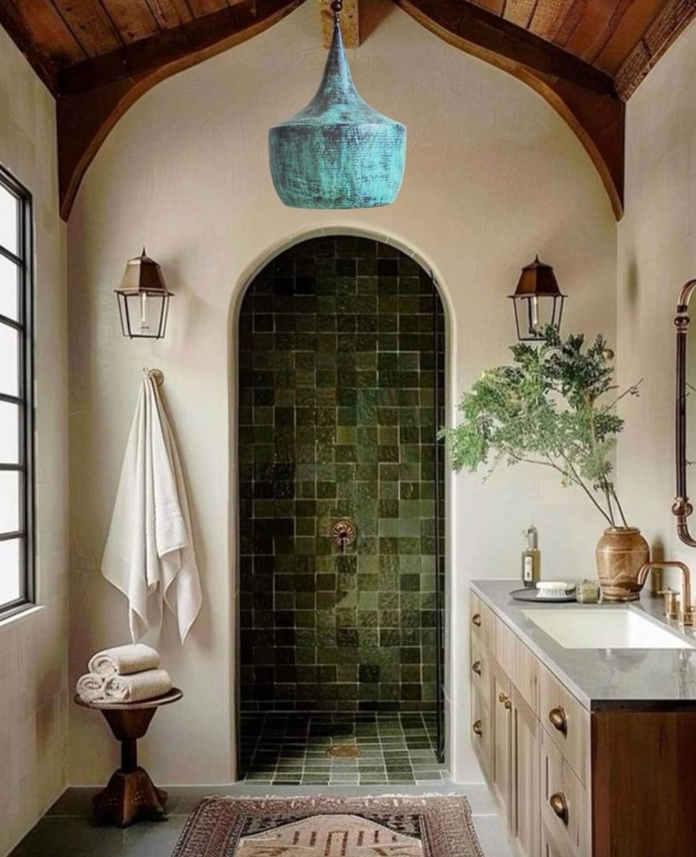 Rustic bathroom with green-tiled shower, wooden vanity, and blue pendant light.