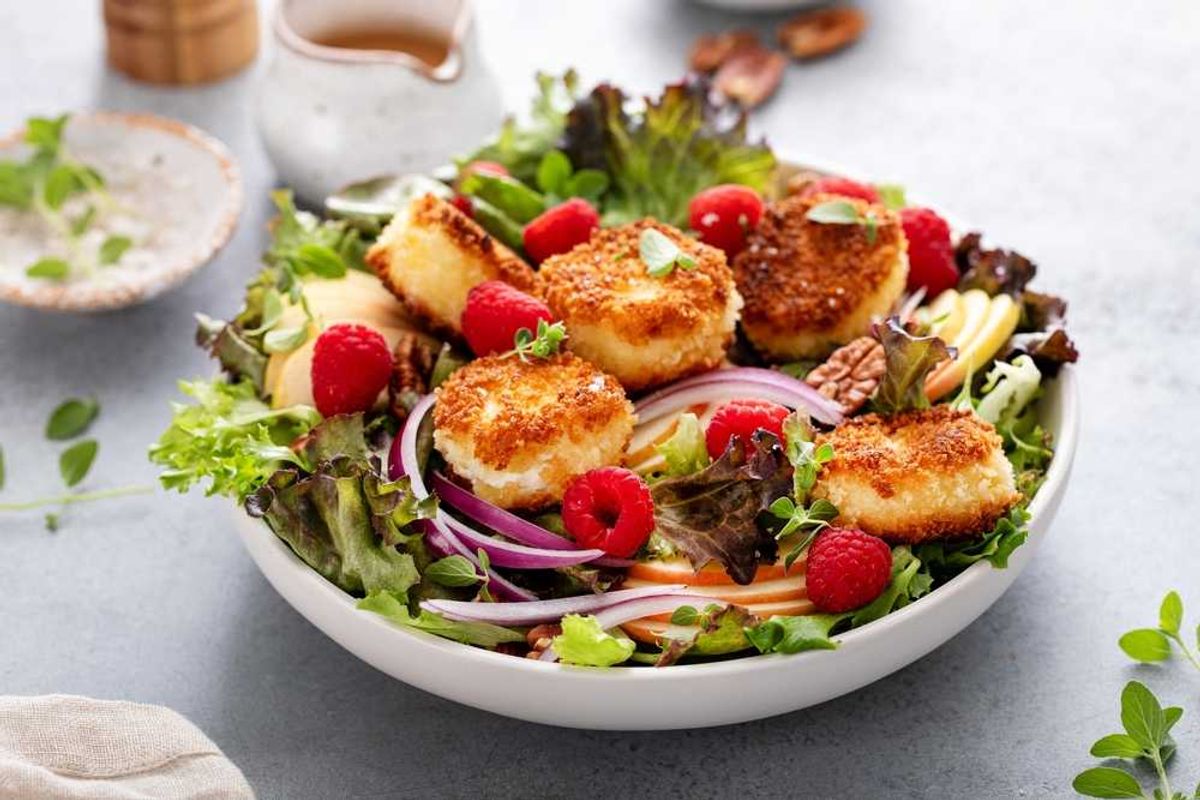 Salad with breaded cheese, raspberries, mixed greens, apple slices, and red onion.