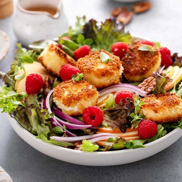 Salad with breaded cheese, raspberries, mixed greens, apple slices, and red onion.