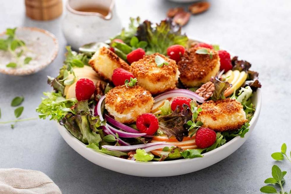 Salad with breaded cheese, raspberries, mixed greens, apple slices, and red onion.