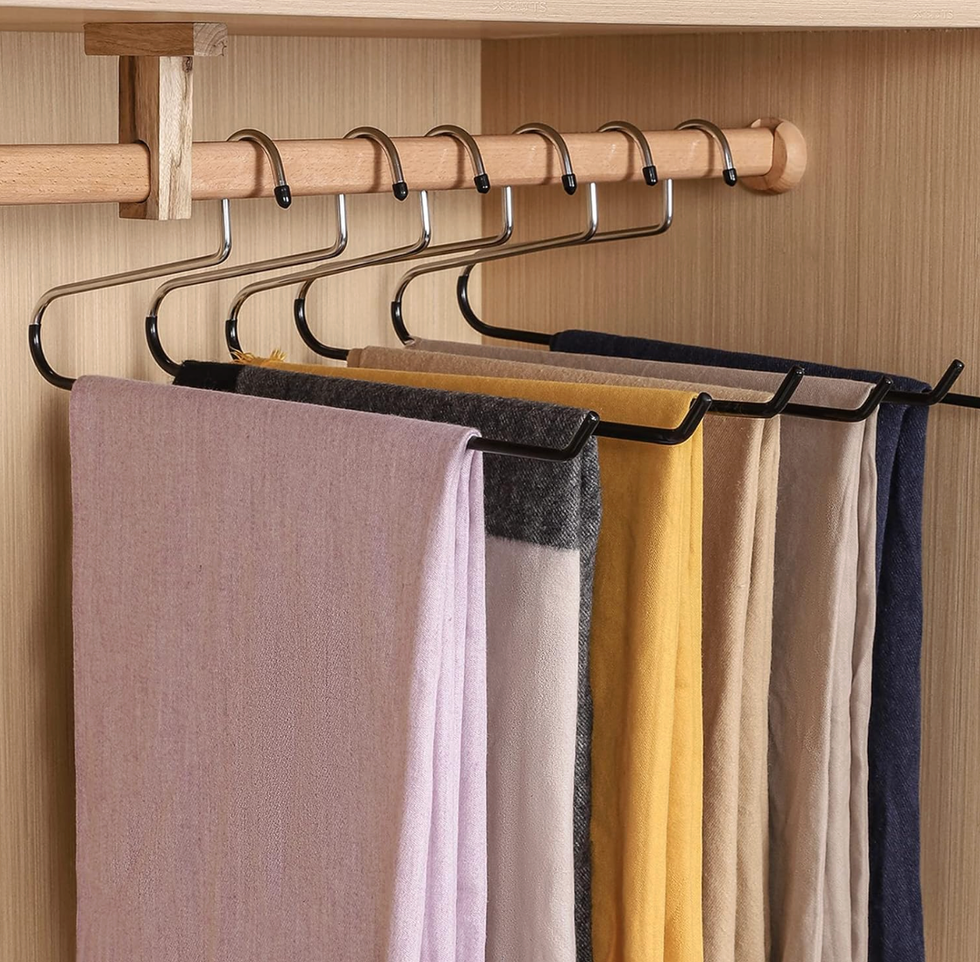 Scarves in various colors neatly hanging on metal hooks in a wardrobe.