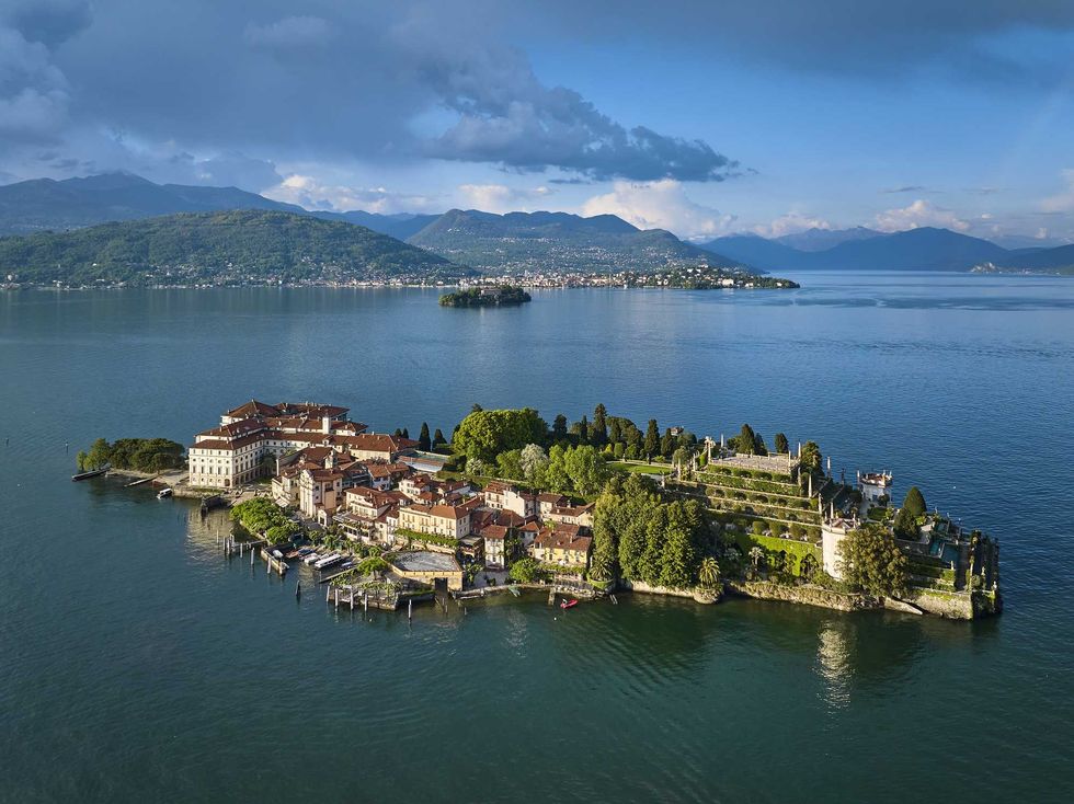Scenic aerial view of an island with historic buildings and lush greenery, surrounded by a lake.