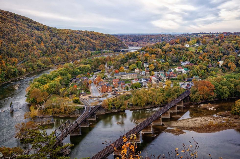 Scenic view of a small town by a river surrounded by colorful autumn foliage.