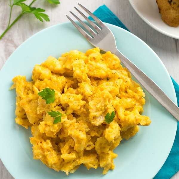 Scrambled eggs on a light blue plate with a fork, garnished with parsley.
