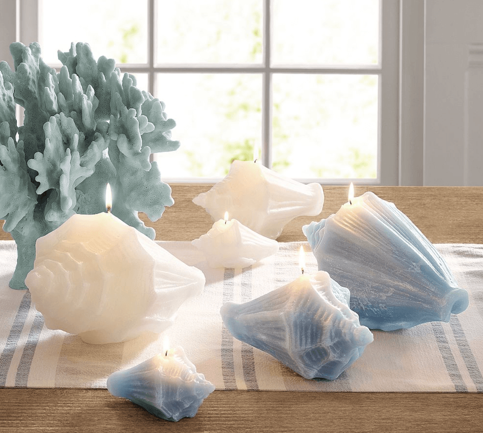 Sea-themed candles and coral decor on table by a window.