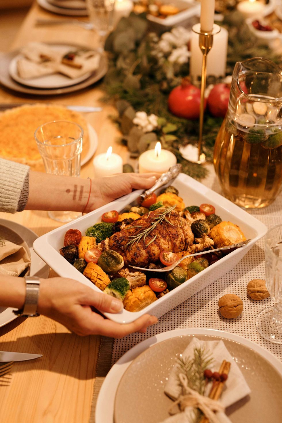 Serving roasted chicken and vegetables at a festive, candlelit dinner table.