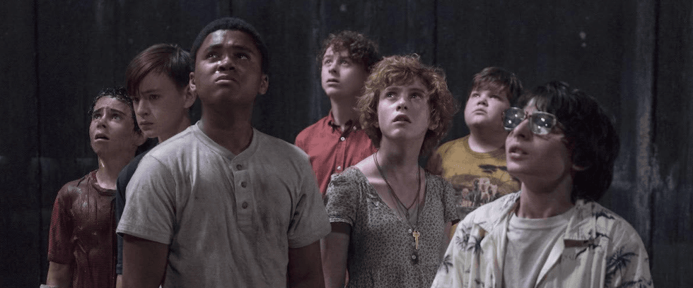 Seven children look up in awe and concern in a dim setting.